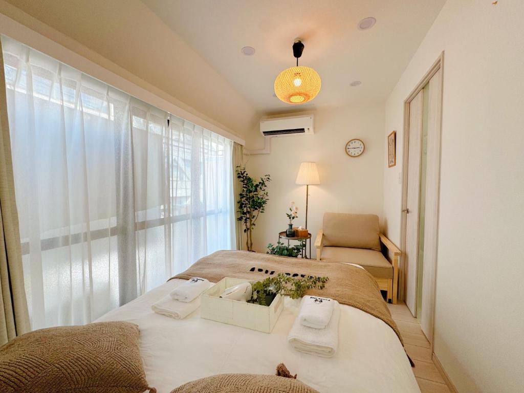a bedroom with two beds and a chair and a window at Sky Home新宿 in Tokyo