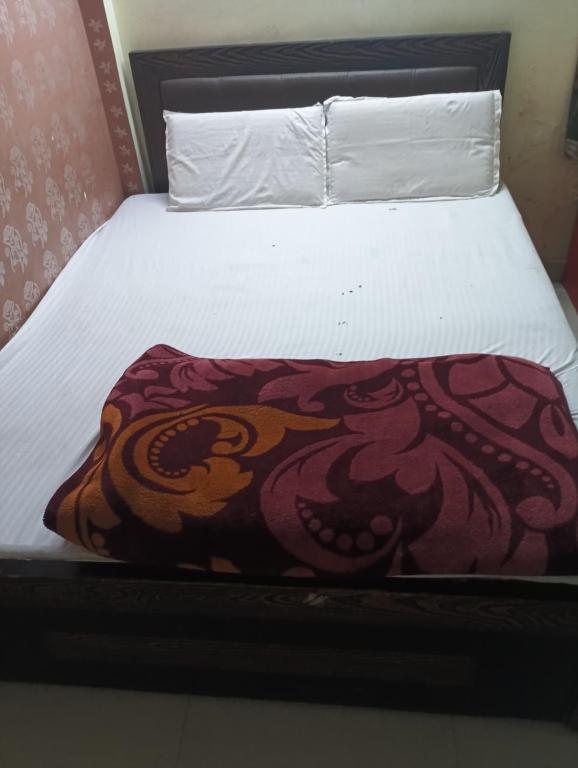a bed with a blanket on top of it at Shri Krishna Guest House in Mathura