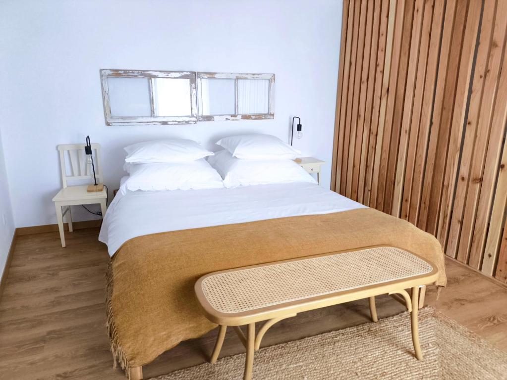 a bedroom with a large bed with a bench on it at O Refúgio do Pim in Horta
