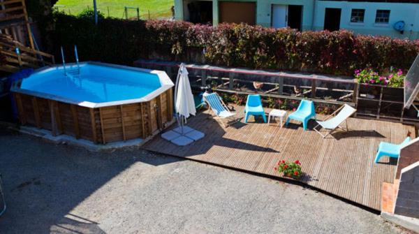 a swimming pool with chairs and an umbrella at Gîte Eugénie in Aspach-le-Bas