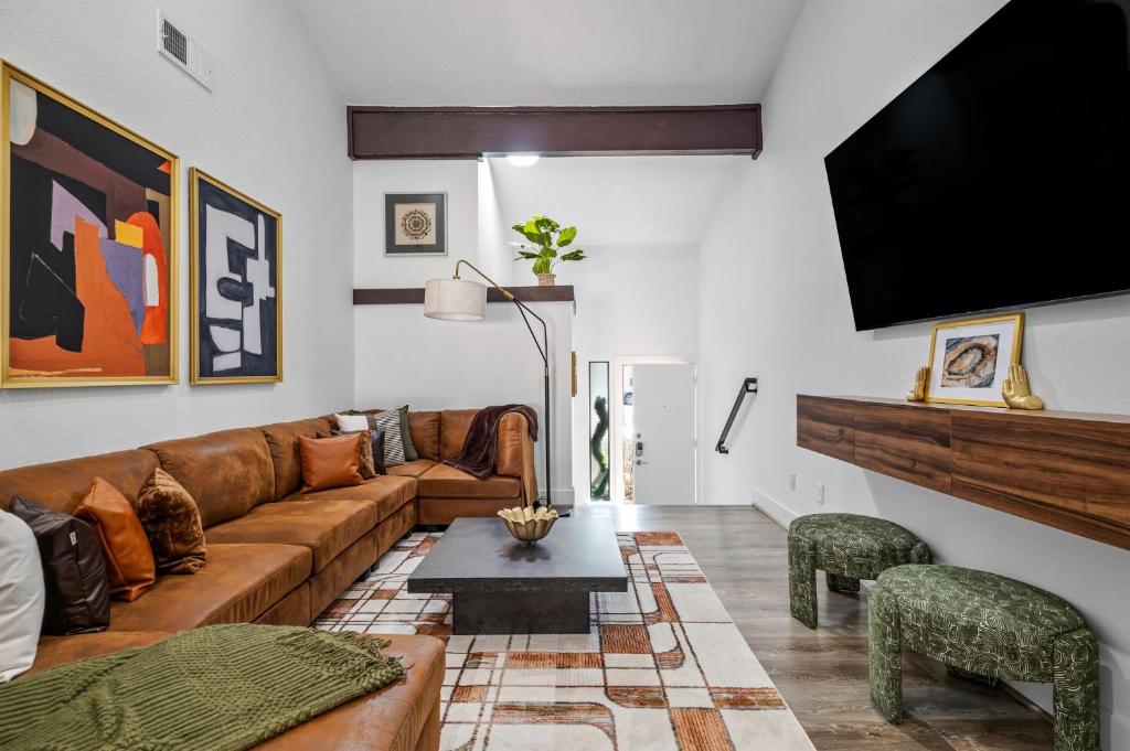 a living room with a couch and a flat screen tv at The Orange Door - Two Homes - Plunge Pool in Austin