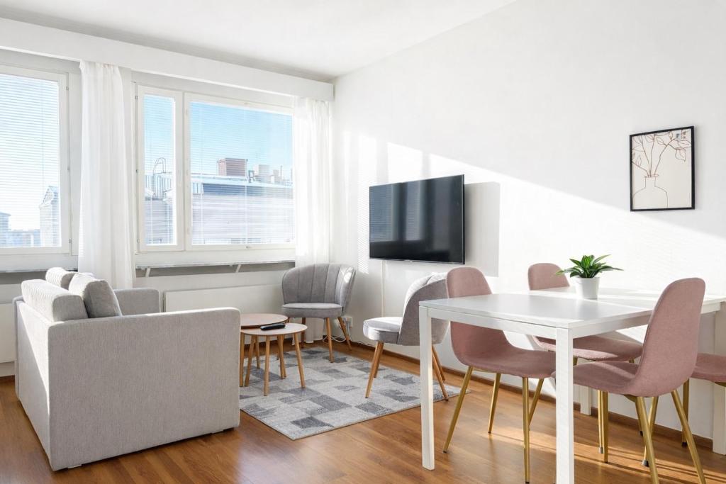 a living room with a table and chairs and a tv at Helmi Pori Centrum in Pori