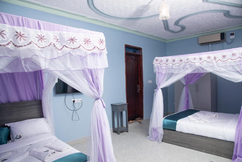 a bedroom with two beds and purple curtains at Legacy Chillout Kasese in Kasese