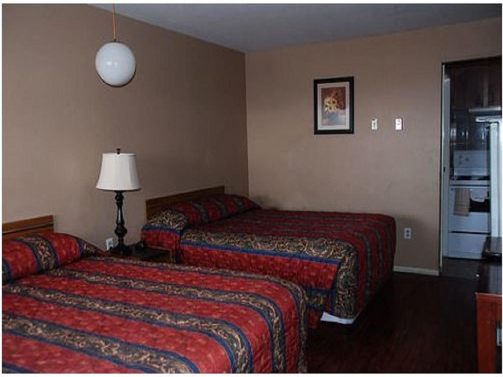 a hotel room with two beds and a lamp at Best Lodge Motel in Lloydminster