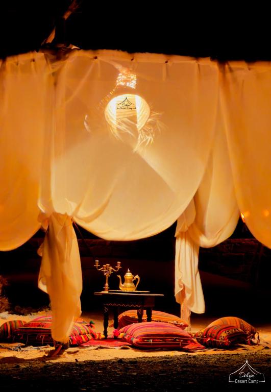 a room with a table and white curtains and a table with a table at Dihya Luxury Camp in Merzouga