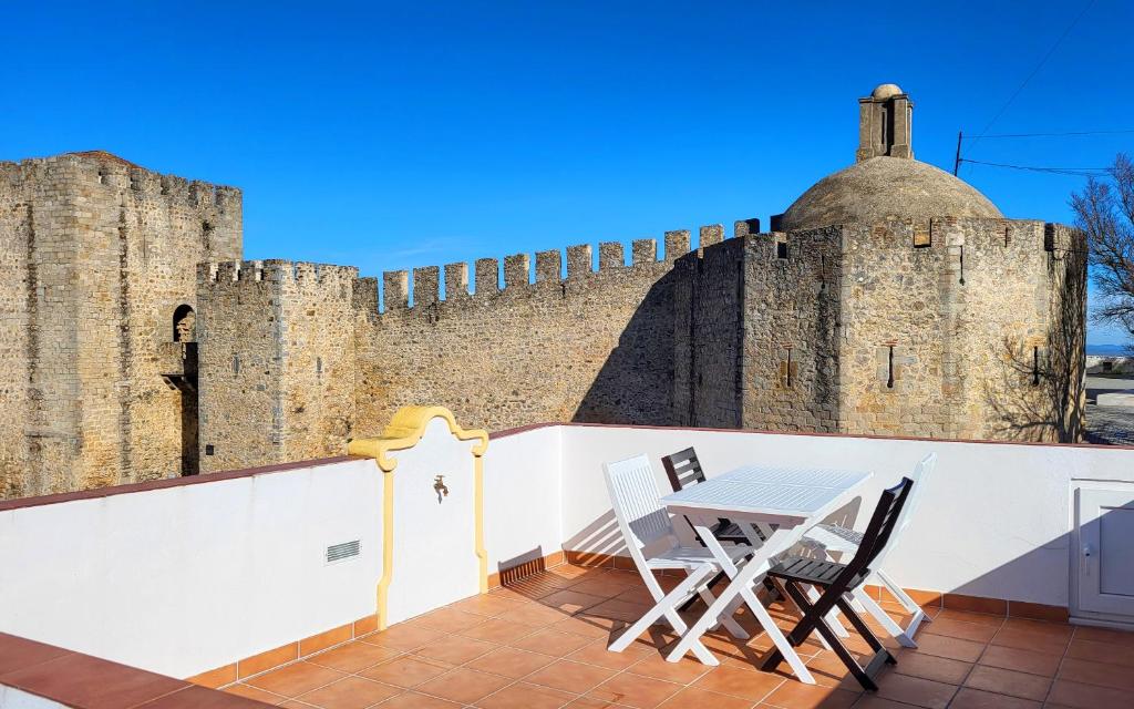 a table and two chairs on a balcony with a castle at Casa Elvas Antiqua in Elvas