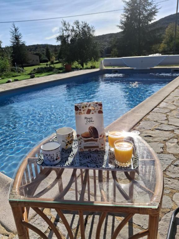 a tray of food and drinks on a table next to a pool at Gîte Les hauts de Lenaly in Les Vans