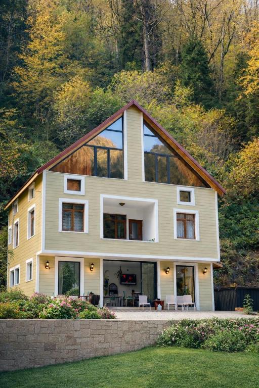 a large house with glass windows on a hill at Nanus Ayder Bungalow and Breakfast in Çamlıhemşin