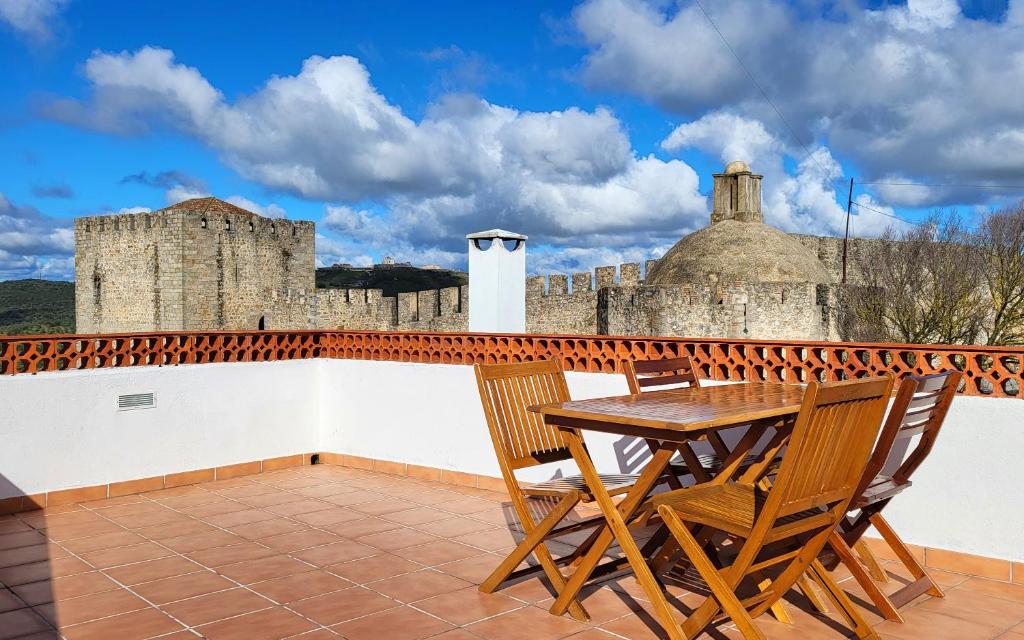 a wooden table and chairs on a balcony with a castle at Casa Miradouro das Beatas in Elvas