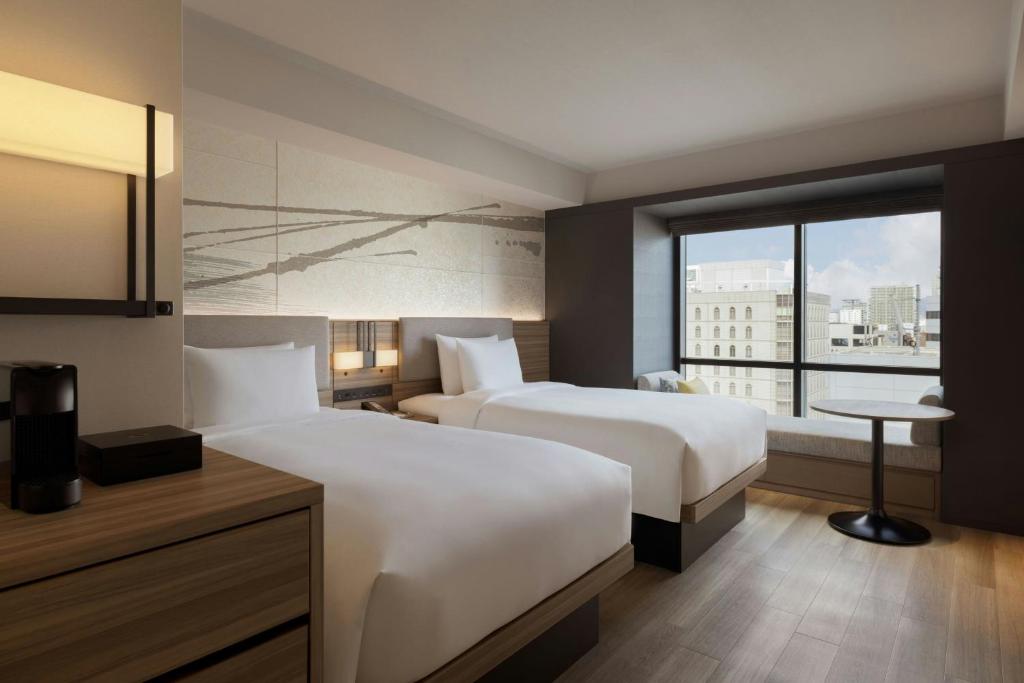 a hotel room with two beds and a window at Courtyard by Marriott Osaka Honmachi in Osaka