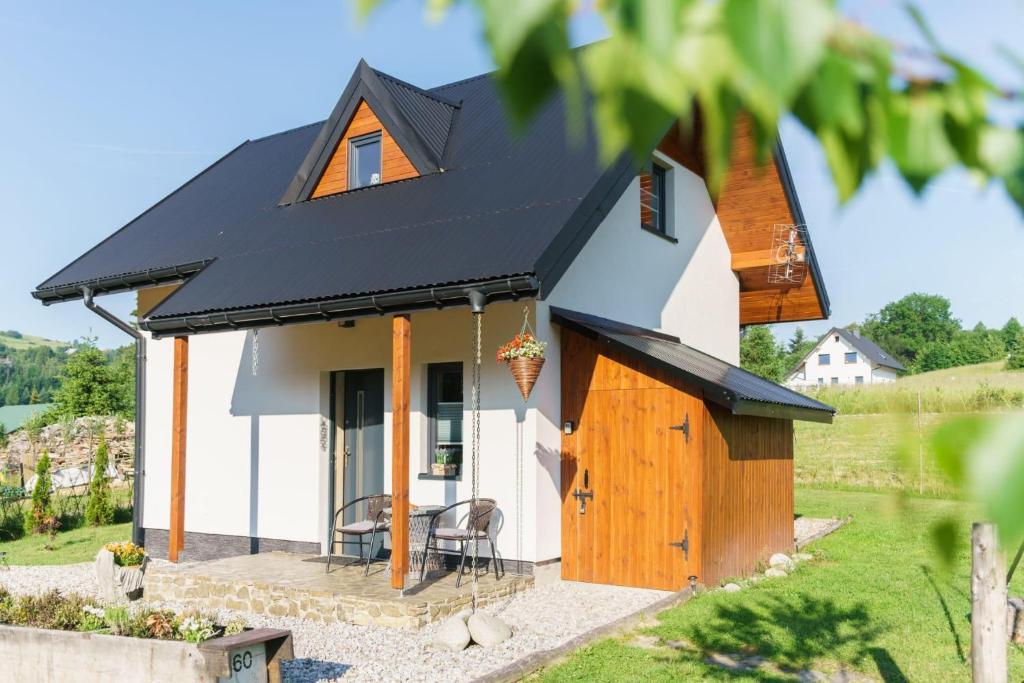 a small white house with a black roof at Domek na Przylasku in Grywałd