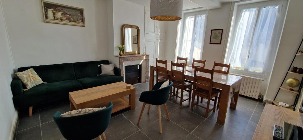 a living room with a green couch and a table at Maison du Gué 2 chambres in Gurgy