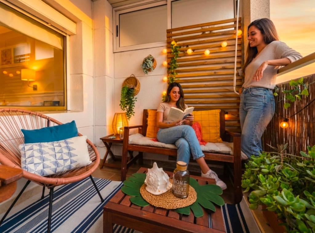 two women standing on a balcony with a woman reading a book at Terraza con encanto Parking Piscina Portaventura in Salou