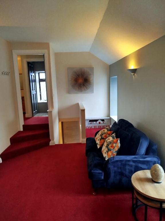 a living room with a blue couch and a red carpet at Aran View Loft in Knockfin Cross Roads