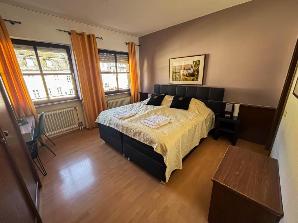 a bedroom with a bed and a table and two windows at Hotel Zunftstube in Saarburg