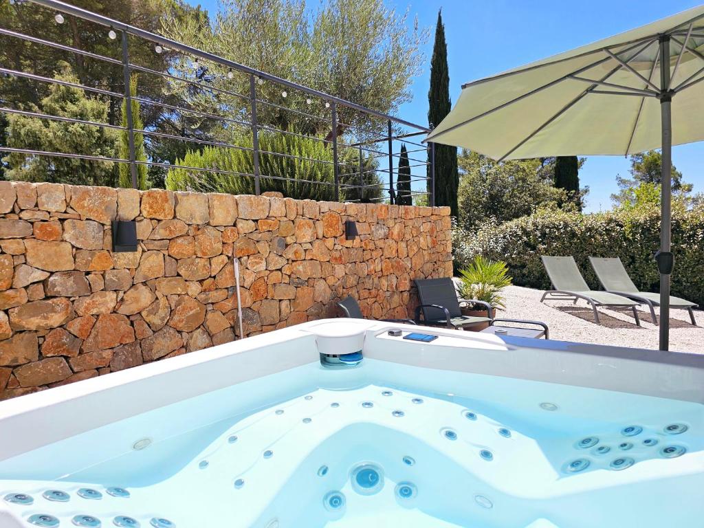 a bath tub in a yard with an umbrella at Suite Sieste en Provence in Entrecasteaux
