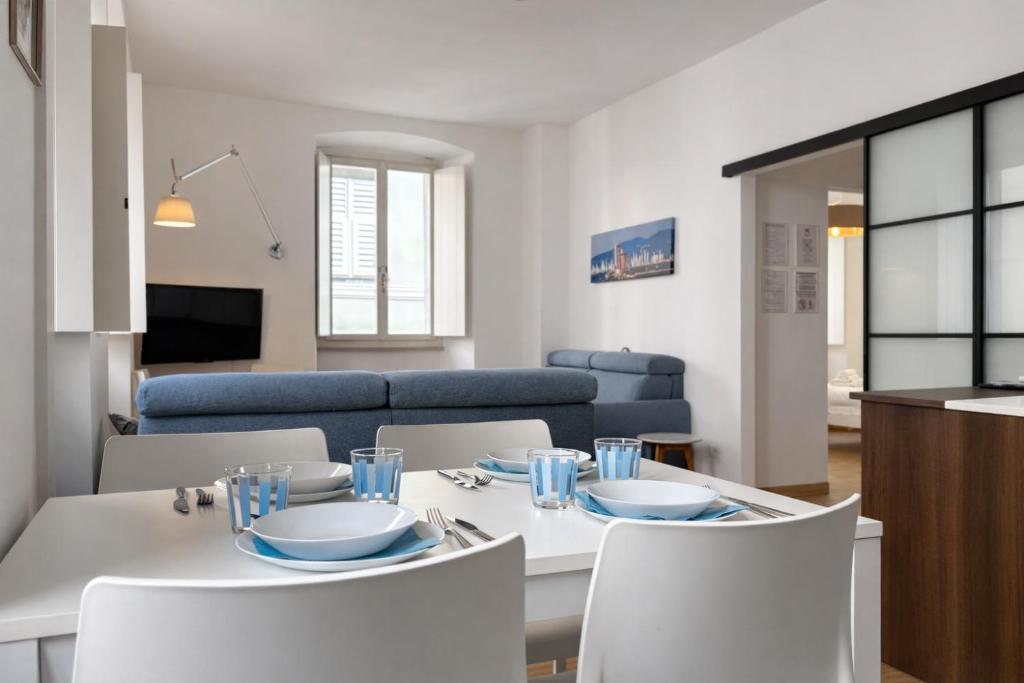 a dining room and living room with a white table and chairs at Bilocale in centro a 1 minuto da Piazza Unità in Trieste