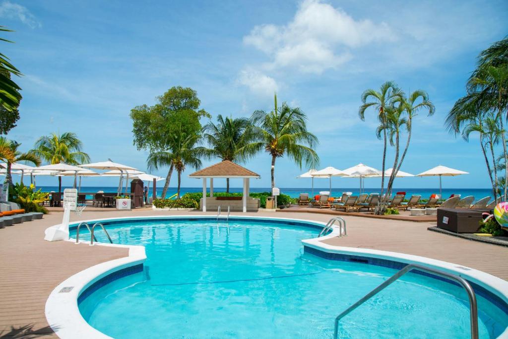 a pool at a resort with the ocean in the background at Tamarind, Barbados, An Autograph Collection All-Inclusive Resort in Saint James