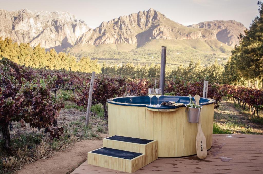 a bath tub sitting on a deck with mountains in the background at Genadendaal Vineyard Villa in Paarl