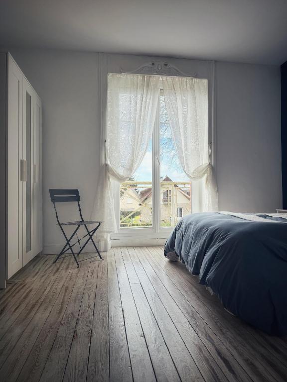 a bedroom with a bed and a window with a chair at Le Chalet du 1er étage, Appartement de charme de 80m2, 2 chambres in Bagnoles de l'Orne