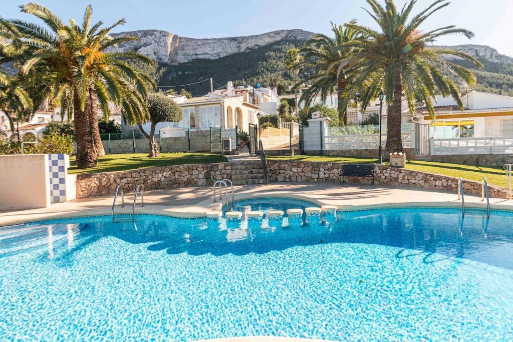 a large swimming pool with palm trees and a house at The Denia Hideaway in Denia