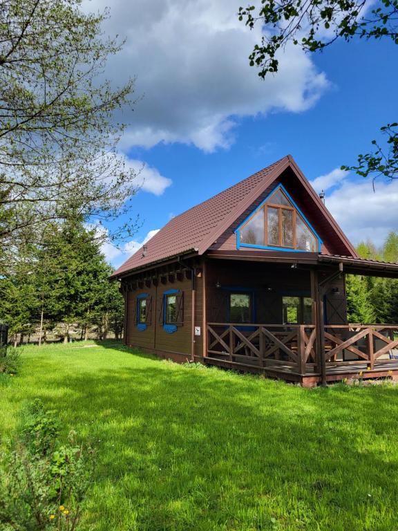 a log cabin with a grassy field in front at Siedlisko Ptasie Trele 2 in Jerutki