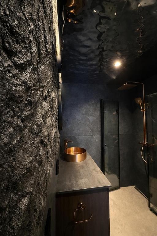 a bathroom with a sink and a stone wall at Studio 28 in Narvik