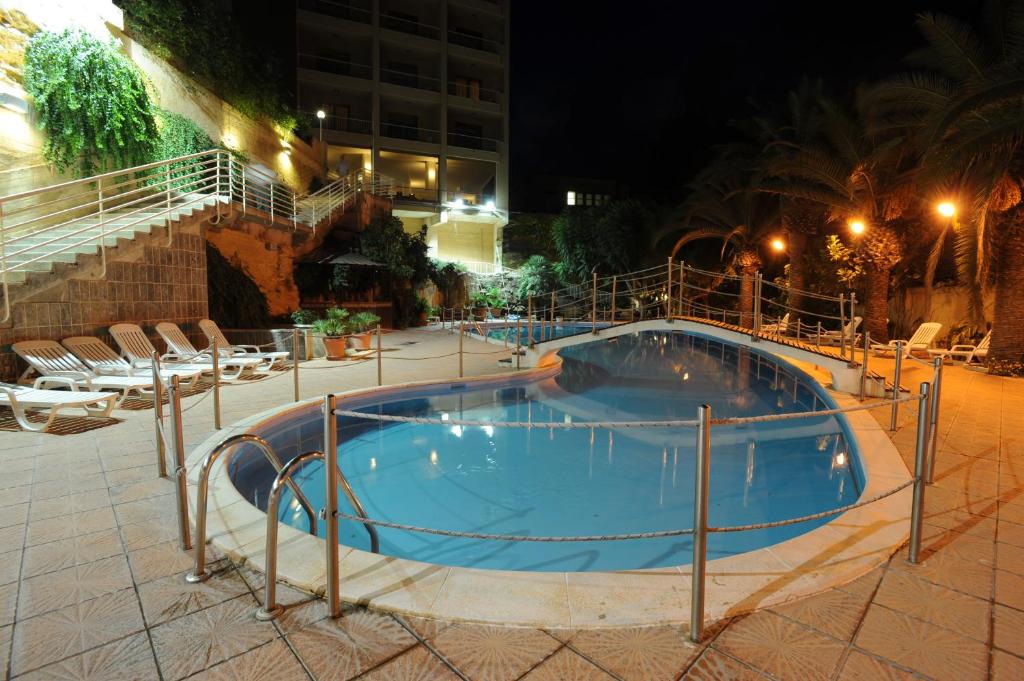 una piscina notturna con sedie intorno di Hotel President a Marsala