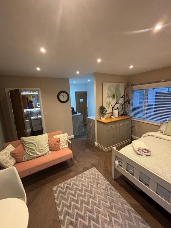 a bedroom with a bed and a couch and a clock at 1 double bed studio with private access and parking in Plymouth