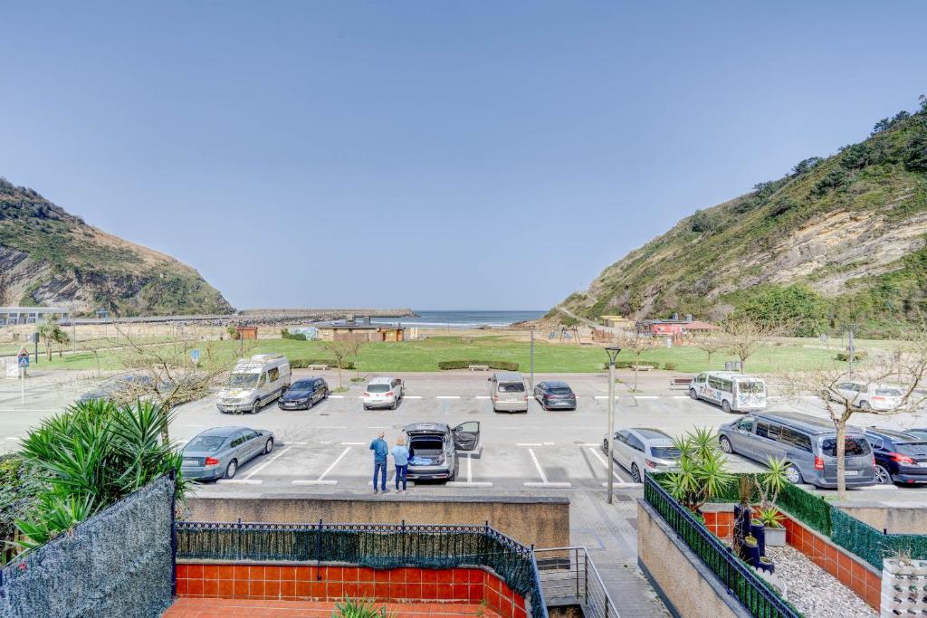 a parking lot next to a beach with cars parked at Orio Playa in Orio