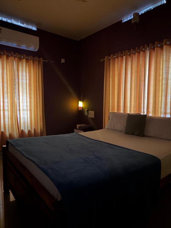 a bedroom with a large bed in front of curtains at Mud apples in Varkala