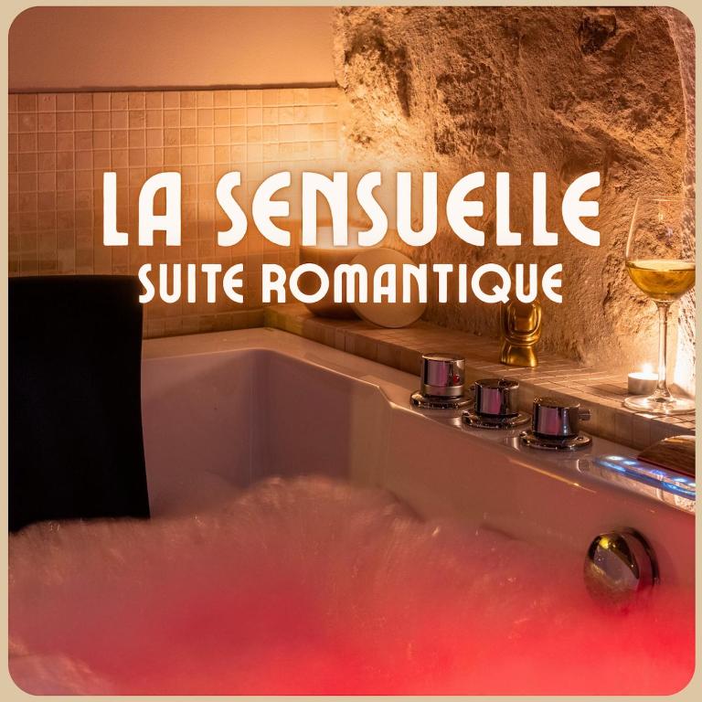 a bath tub with a glass of wine next to it at La Sensuelle Suite with spa in Vendres