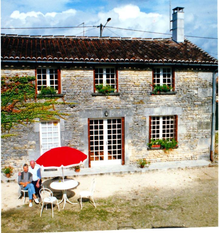 two people sitting at a table in front of a stone house at Chez PRESSOIRS in Mesnac