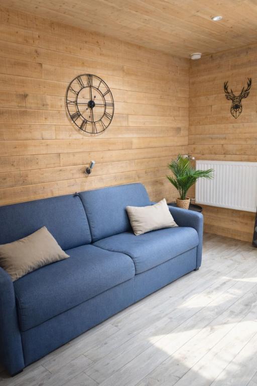 un divano blu in una stanza con un orologio sul muro di Studio cosy SUPERDEVOLUY a Le Dévoluy