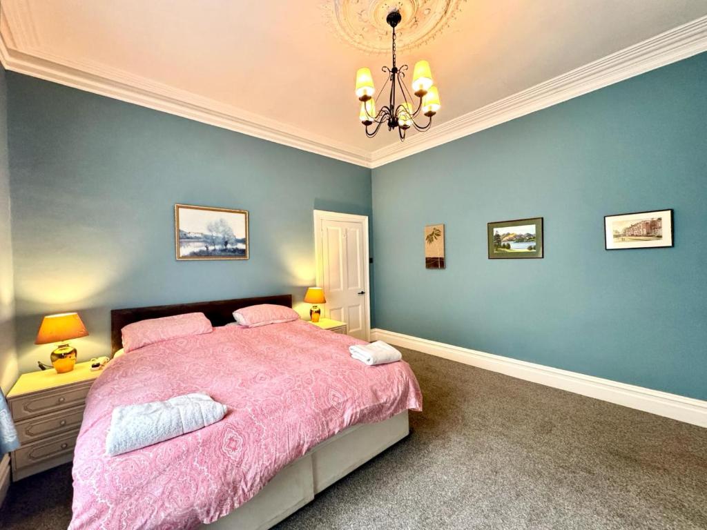 a bedroom with a pink bed and blue walls at Regents Chambers in Bishop Auckland