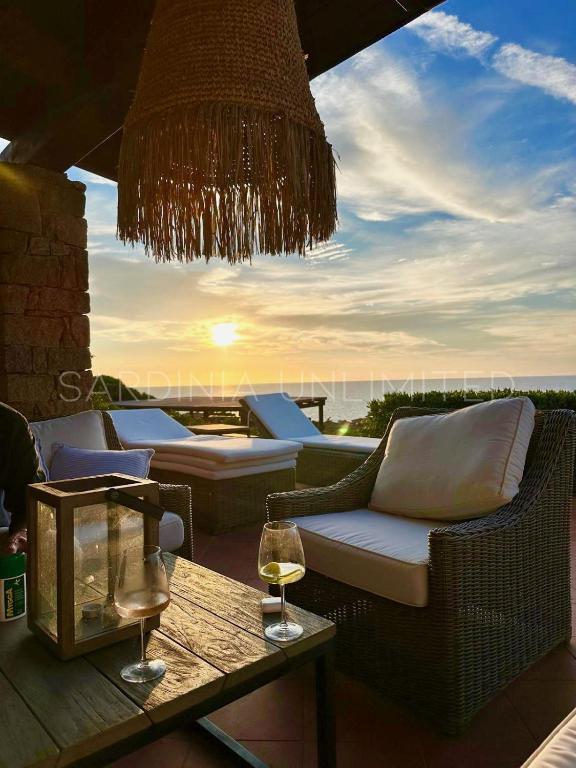a patio with couches and a table with a glass of wine at Li Junchi in Costa Paradiso