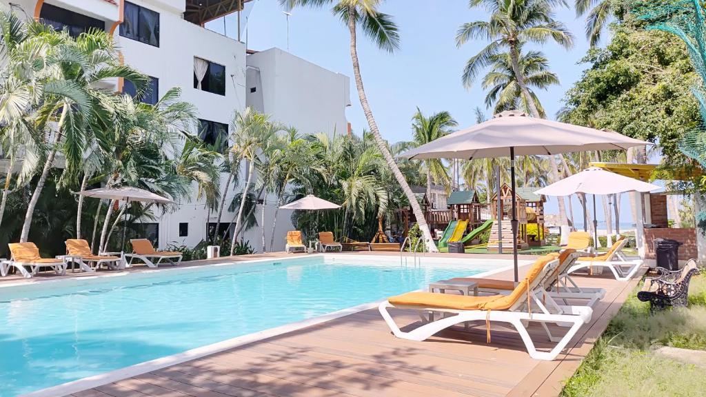 a swimming pool with chairs and umbrellas next to a building at Surf Olas Altas in Puerto Escondido