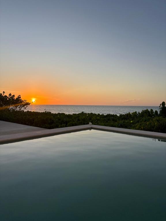 a sunset over the ocean with a swimming pool at Casa Portofino in Chuburná