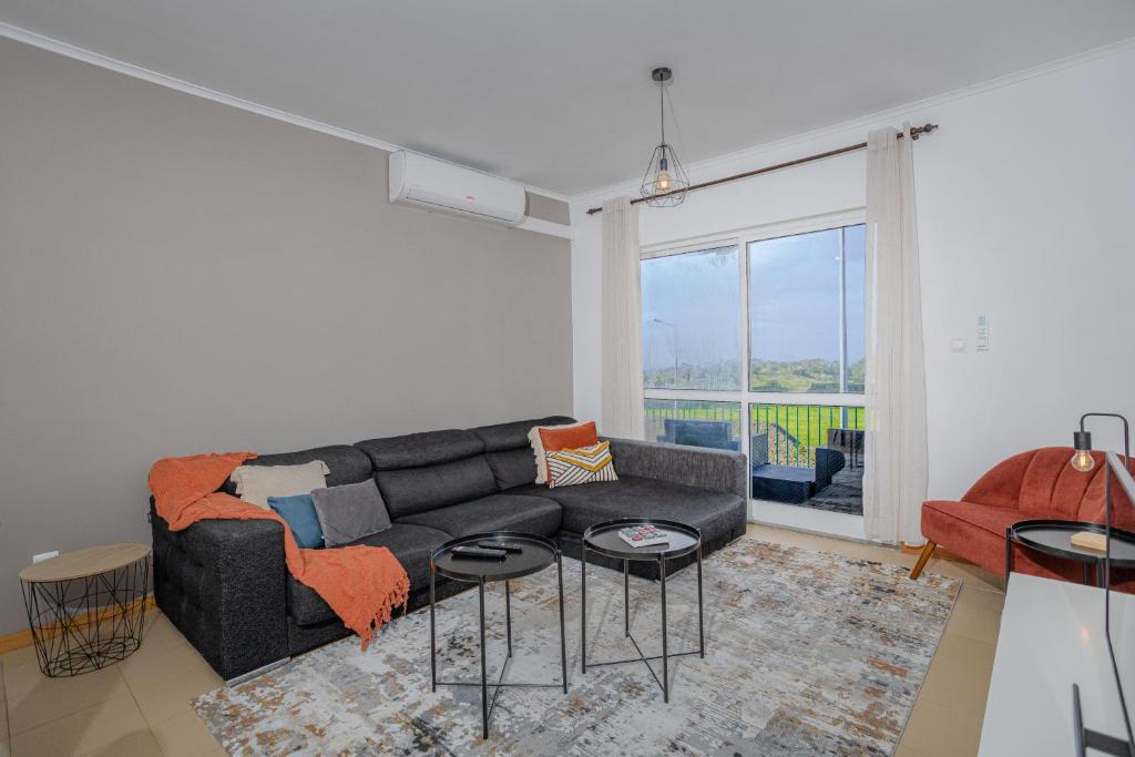 a living room with a black couch and a large window at Azorina Lodge in Ponta Delgada
