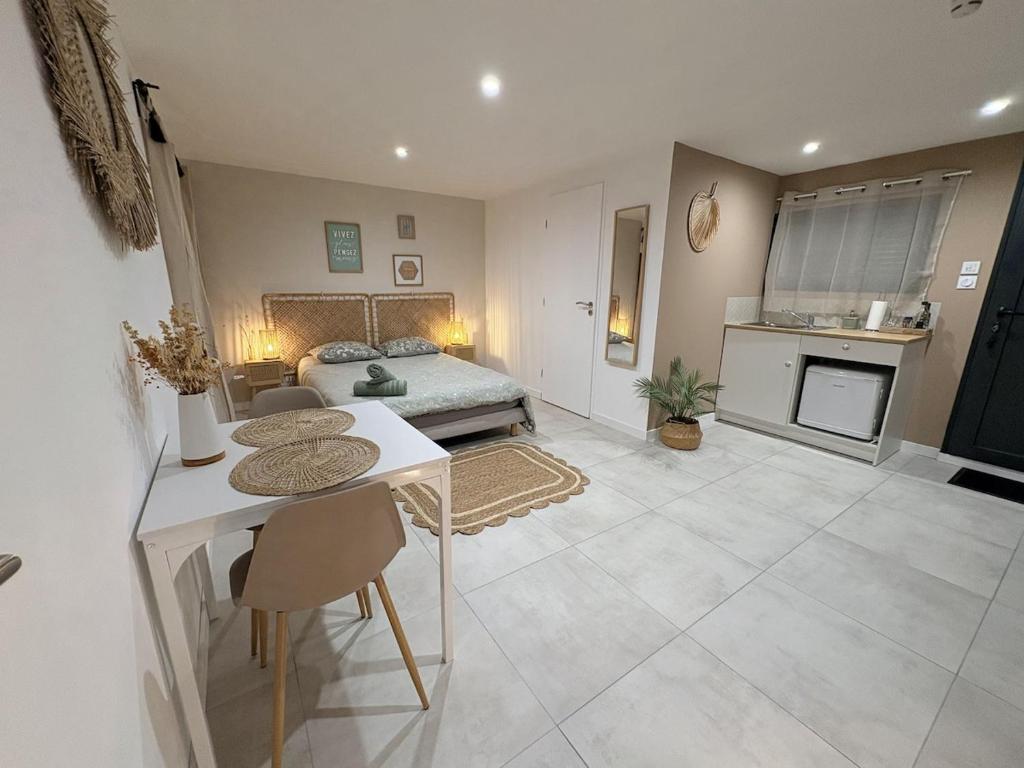 a bedroom with a bed and a table and a kitchen at Studio indépendant a 20min des plages in Castelnau-de-Guers