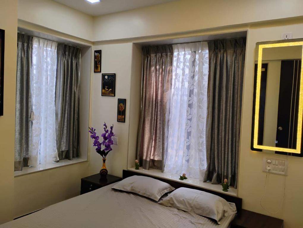 a bedroom with a bed and two windows at the prestige ganga in Solapur