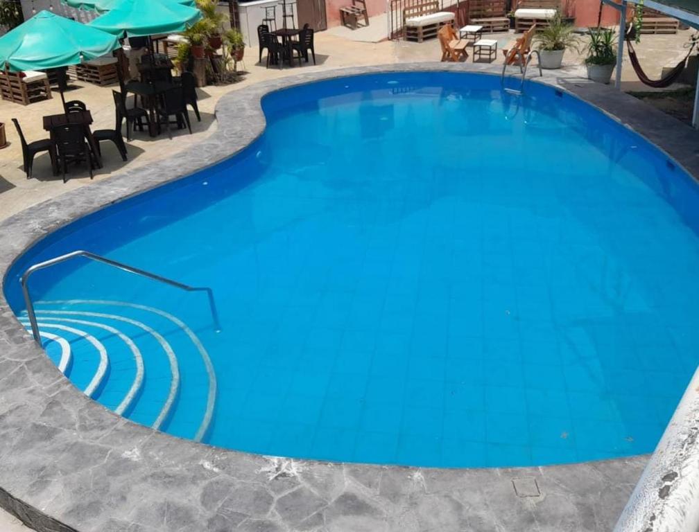 a large blue swimming pool with chairs and tables at the silva house in Huacachina