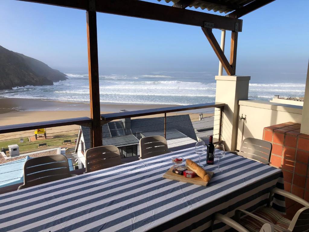 a table on a balcony with a view of the beach at Toms Cabin in Herolds Bay