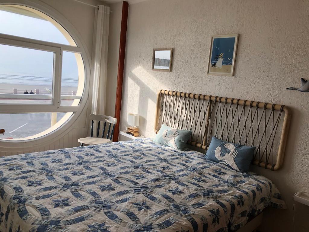 a bedroom with a bed with a large window at Appartement face mer in Quend