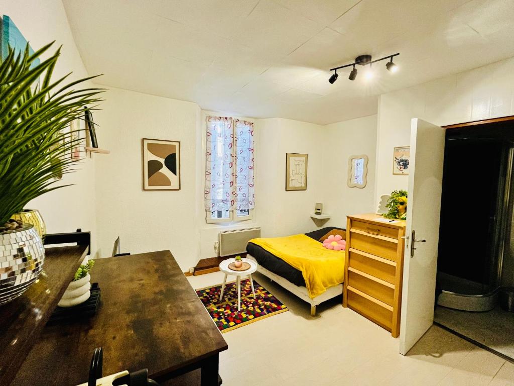 a small bedroom with a yellow bed and a table at Le Cocon 54 Studio à Rives Parking facile in Rives
