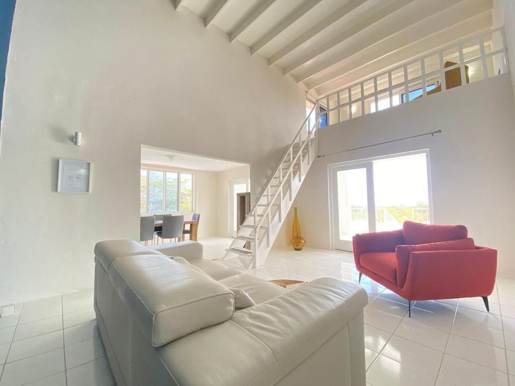 a living room with a couch and a red chair at Aruba Villa on a Hill in Savaneta