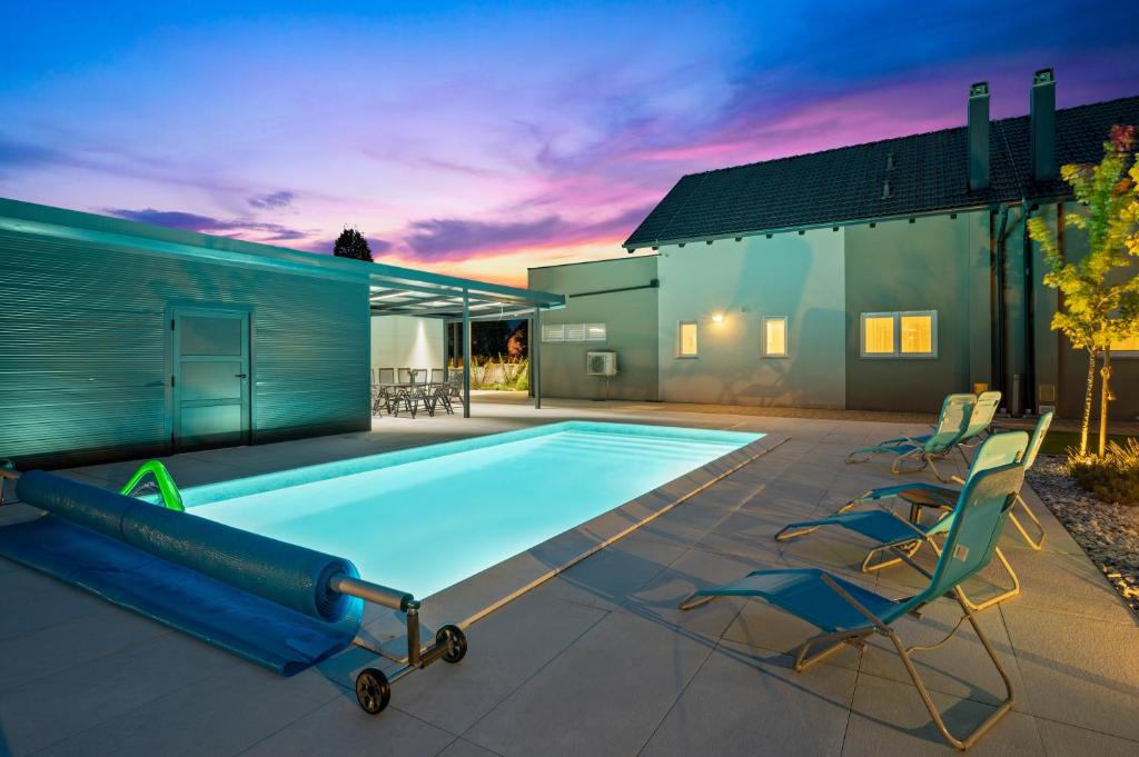 a swimming pool with two chairs and a house at House Degenia in Lovinac