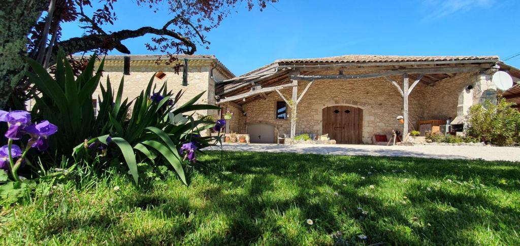 a house with a yard with purple flowers in the grass at La Maison d'ART in Lacour