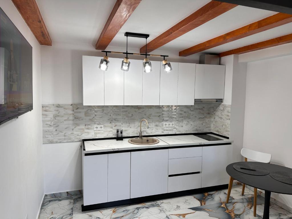 a kitchen with white cabinets and a sink and a table at Arius King in Satu Mare