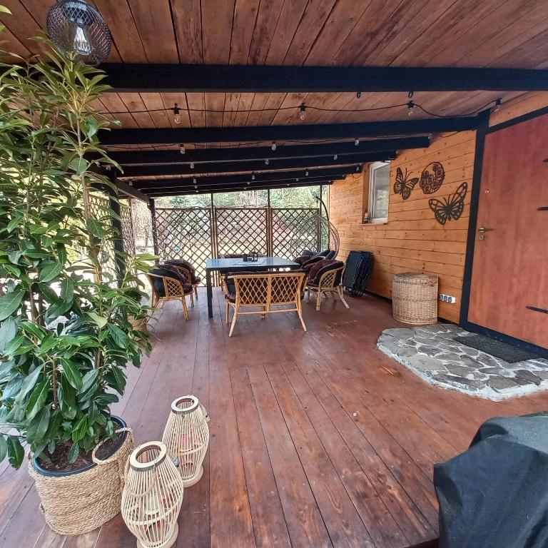 a patio with a table and chairs on a wooden deck at Jeziorskie Zacisze & balia in Łyszkowice